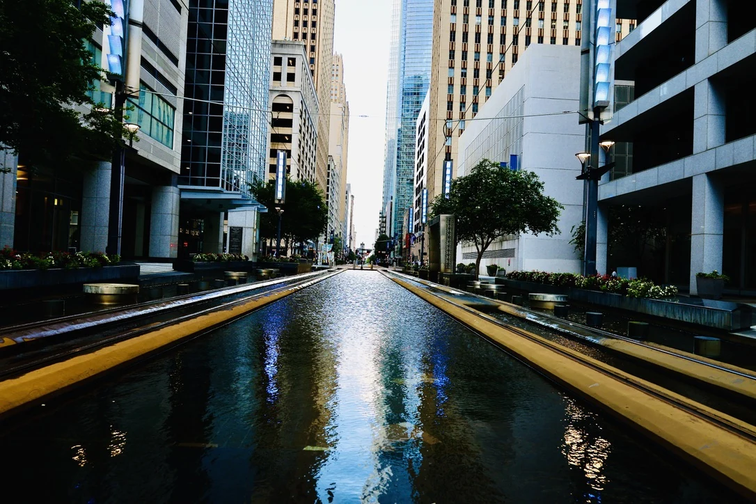 Downtown Houston street with a reflecting water feature between office towers
