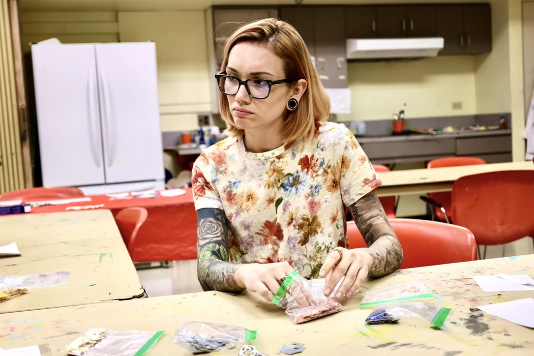 The same subject focused on craft work at a table, environmental portrait