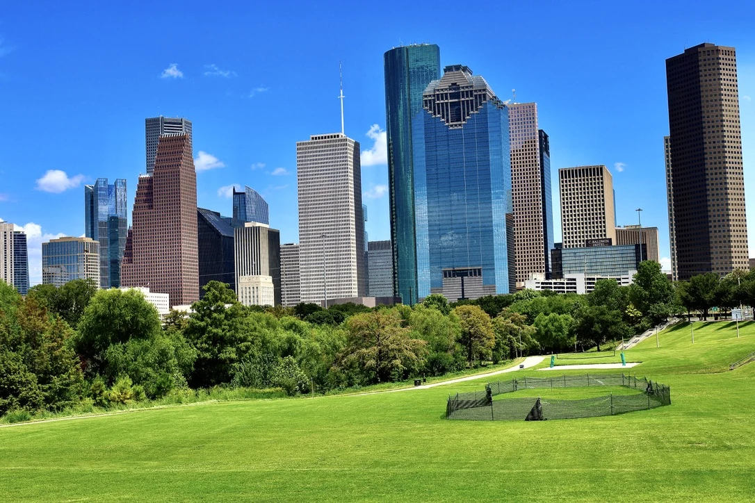 Houston downtown skyline rising behind a green park lawn
