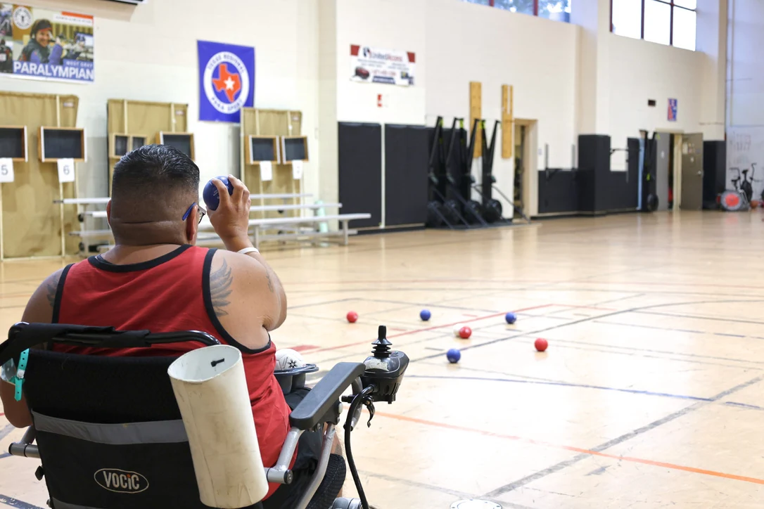 Adaptive athlete in a sports wheelchair taking aim during a boccia match