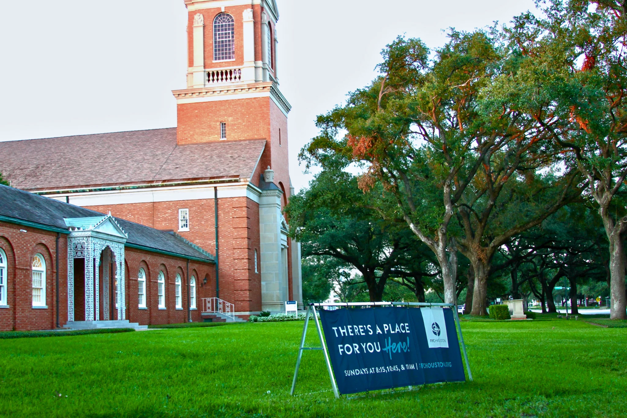 A chapel exterior with a welcoming "there's a place for you" sign on the lawn