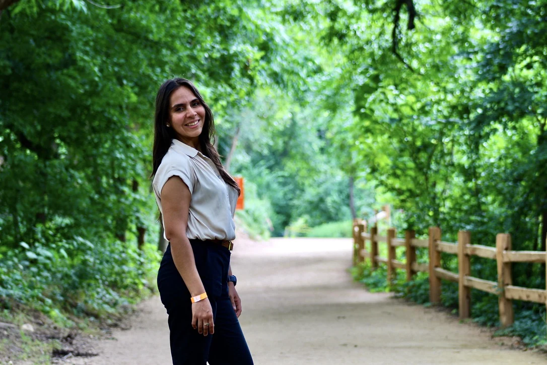Woman glancing back along a wooded trail, environmental portrait
